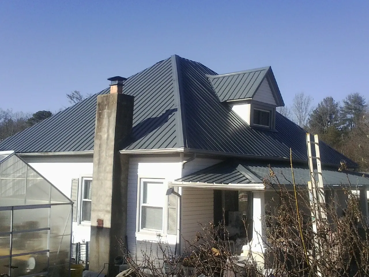 Dark blue standing seam metal roof on a white farmhouse with dormer — Slate & Tile Roof Repair by Roofing Brothers in Marietta