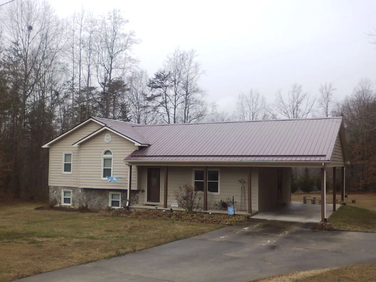 Burgundy metal roof on a tan split level home with an attached carport in Marietta