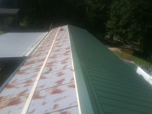 Old rusted panels beside newly installed green metal roofing — Wind Damage Roof Repair by Roofing Brothers in Marietta