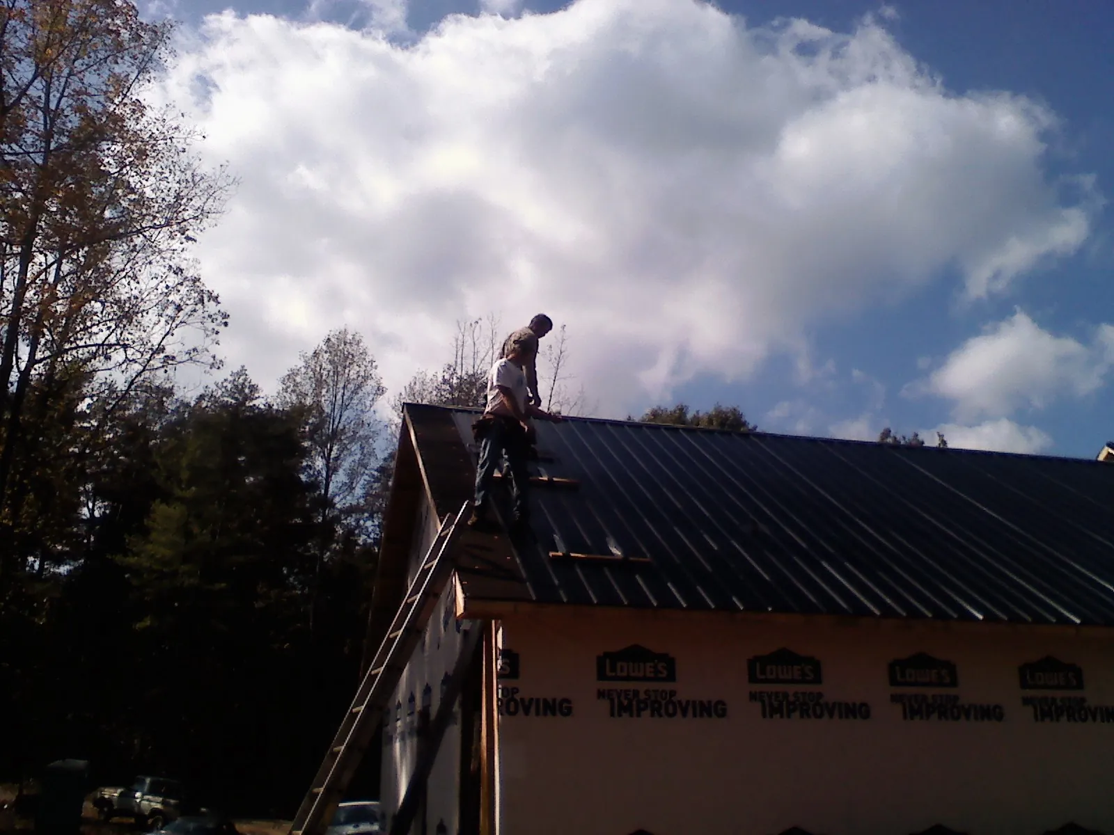 Roofer fastening dark metal panels high against a cloudy sky, from a Roof Inspection job in Marietta