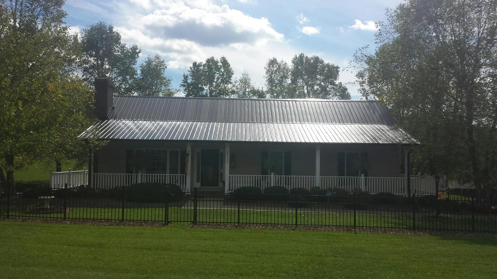 Gray metal roof on a brick ranch with a full width front porch — Gutter Guard Installation work by our crew in Marietta